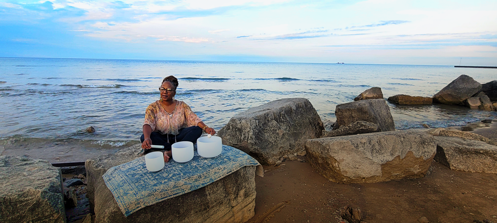 Kaiyah Allison with singing bowls by the ocean